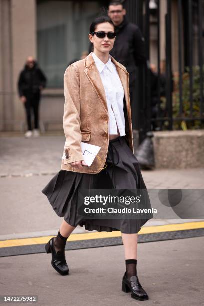 Amelia Gray wears a beige denim Miu Miu blazer, white shirt, black skirt, black loafers and blue Miu Miu bag, outside Miu Miu, during Paris Fashion...