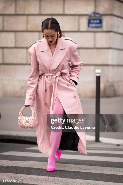 Tiffany Hsu wears a pink leather trench coat, pink Miu Miu bag, fuchsia tights and fuchsia heels, outside Miu Miu, during Paris Fashion Week -...