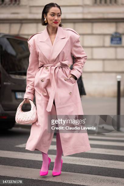 Tiffany Hsu wears a pink leather trench coat, pink Miu Miu bag, fuchsia tights and fuchsia heels, outside Miu Miu, during Paris Fashion Week -...