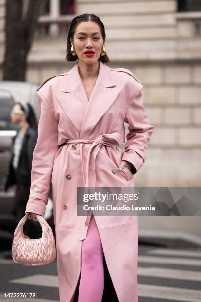 Tiffany Hsu wears a pink leather trench coat, pink Miu Miu bag, fuchsia tights and fuchsia heels, outside Miu Miu, during Paris Fashion Week -...