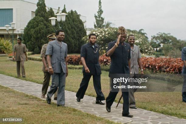 President Mobutu Sese Seko salutes as he and his entourage walk in the grounds of his mansion in Kinshasa, Zaira, on October 27th, 1974.