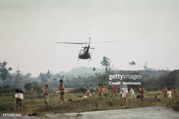 View of children on the ground as a helicopter takes off in South Vietnam after being loaded with supplies by government troops on February 4th, 1975.