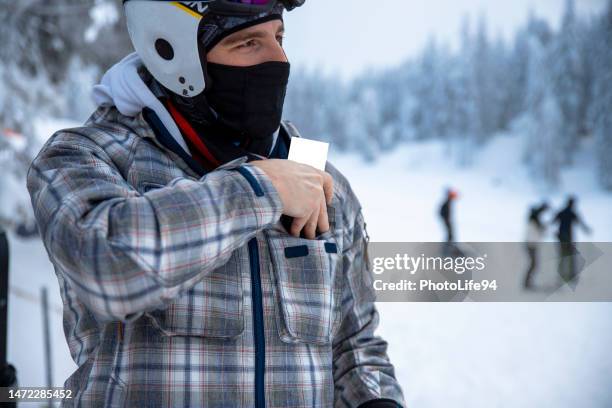 un homme a mis le forfait de ski dans une poche de veste de ski - col photos et images de collection