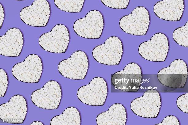 white pills in shape of heart of purple background - health and safety icons stock pictures, royalty-free photos & images