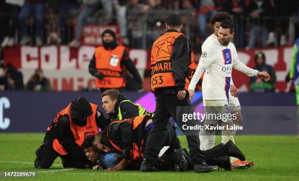 Security staff eject a streaker over Lionel Messi of Paris Saint-Germain after the UEFA Champions League round of 16 leg two match between FC Bayern...