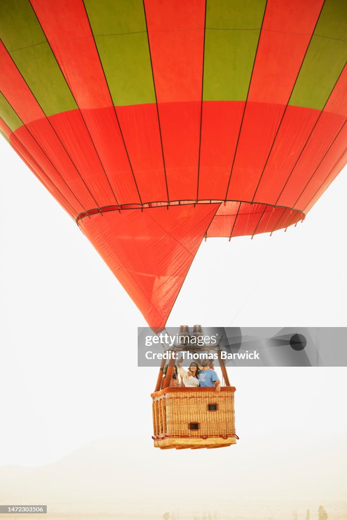 Wide shot of couple taking selfie during sunrise hot air balloon ride