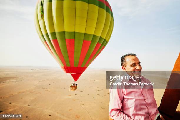 medium shot of smiling senior man on early morning hot air balloon ride - hot air balloon ride stock-fotos und bilder