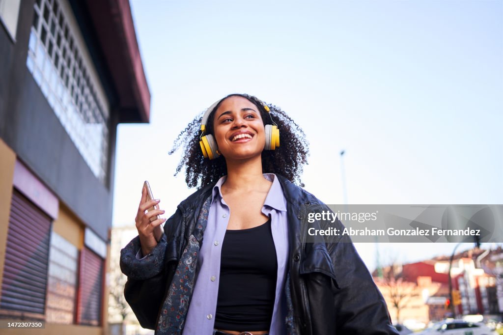 Cheerful woman listening to music with a mobile outdoors
