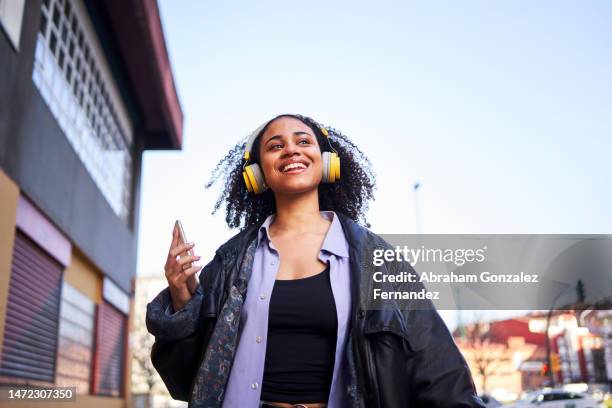 cheerful woman listening to music with a mobile outdoors - the music of david lynch benefiting the 10th anniversary of the david lynch foundation stockfoto's en -beelden