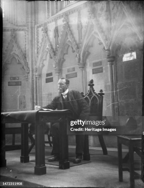 Wells Cathedral, Cathedral Green, Wells, Mendip, Somerset, 1907. The photographer's father, John MacFee, sitting posed in the bishop's chair in Wells...