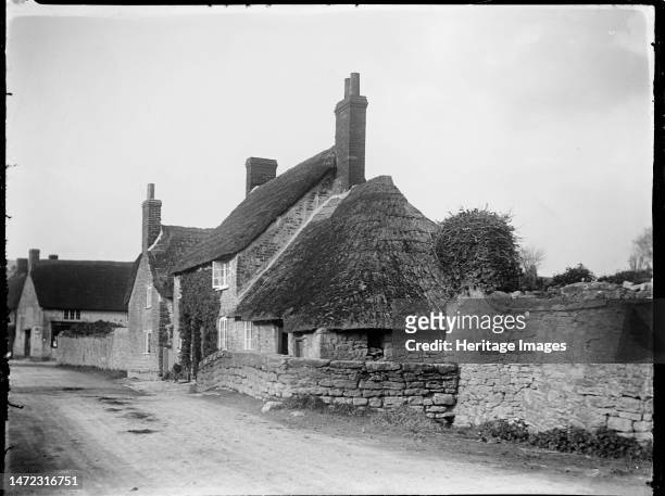 High Street, Burton Bradstock, West Dorset, Dorset, 1922. A thatched cottage on the High Street in Burton Bradstock with a thatched outbuilding...
