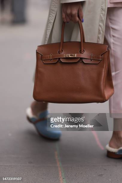 Fashion Week Guest seen wearing a beige long coat, wide pants, big brown Kelly Hermes handbag, Hermes Pantoletten Carlotta fur shoes, outside Hermes...