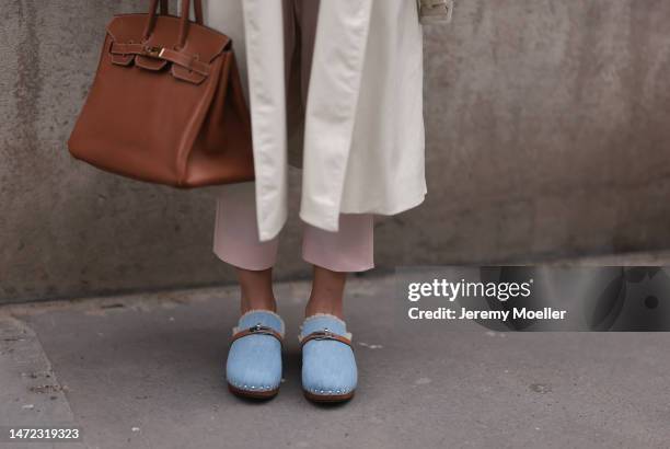 Fashion Week Guest seen wearing a beige long coat, wide pants, big brown Kelly Hermes handbag, Hermes Pantoletten Carlotta fur shoes, outside Hermes...