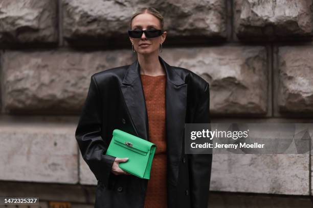 Leonie Hanne wears green Hermes bag, rust brown dress, black long leather coat and black sunglasses, outside Hermes during Paris Fashion Week -...