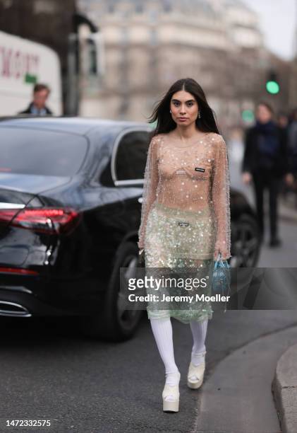Fer Millan Delaroiere seen wearing a transparent glitter sequins dress with a blue shiny bag, white socks and white plateau heels before the Miu Miu...