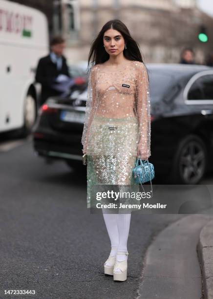 Fer Millan Delaroiere seen wearing a transparent glitter sequins dress with a blue shiny bag, white socks and white plateau heels before the Miu Miu...