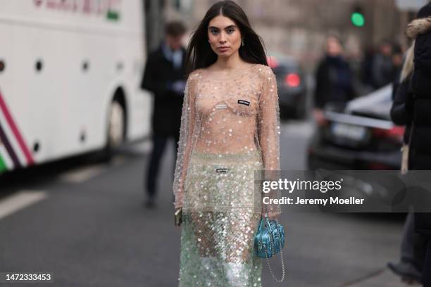 Fer Millan Delaroiere seen wearing a transparent glitter sequins dress with a blue shiny bag, white socks and white plateau heels before the Miu Miu...