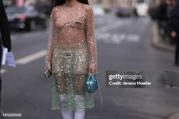 Fer Millan Delaroiere seen wearing a transparent glitter sequins dress with a blue shiny bag, white socks and white plateau heels before the Miu Miu...