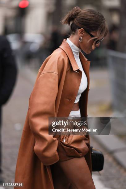 Camila Coelho seen wearing a brown coat and a matching brown mini, dark shades, a cropped white turtle neck and white underwear skirt before the Miu...