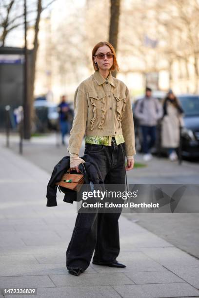 Guest wears brown sunglasses, a beige with ruffled detail buttoned jacket, a pale yellow and green snake print pattern silk shirt, black denim large...