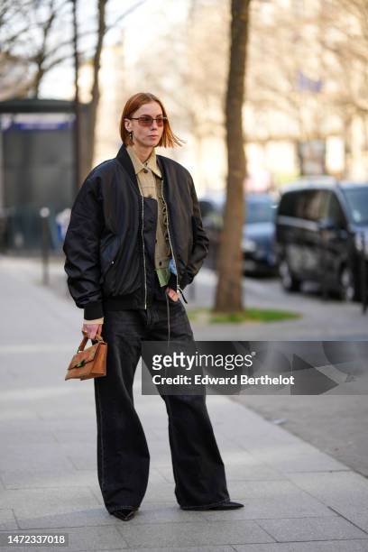 Guest wears brown sunglasses, a beige with ruffled detail buttoned jacket, a pale yellow and green snake print pattern silk shirt, black denim large...