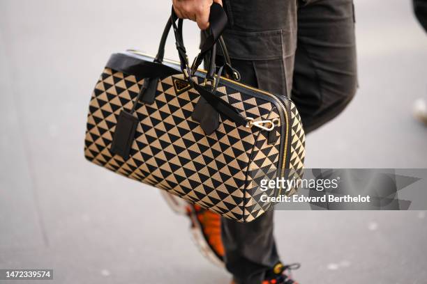 Guest wears a beige and black triangular print pattern handbag from Prada, orange sneakers from Nike , outside The Row, during Paris Fashion Week -...