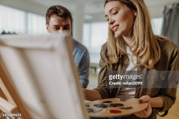 young couple painting at home - house for an art lover stock pictures, royalty-free photos & images