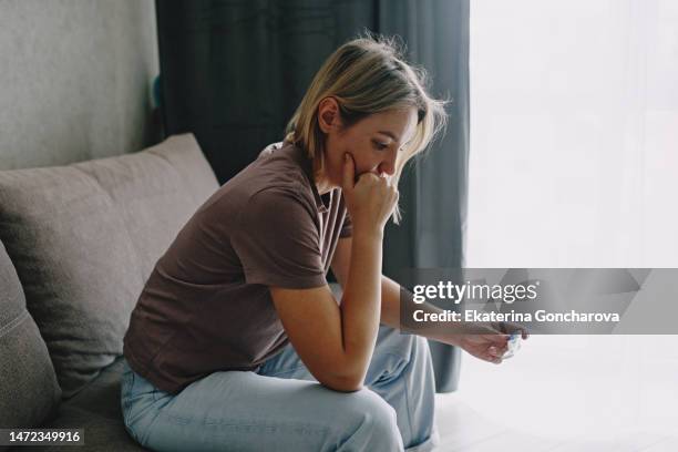 a young woman holds a device reading a pregnancy test. - family planning stock pictures, royalty-free photos & images