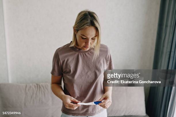 a young woman holds a device reading a pregnancy test. - interior coche photos et images de collection