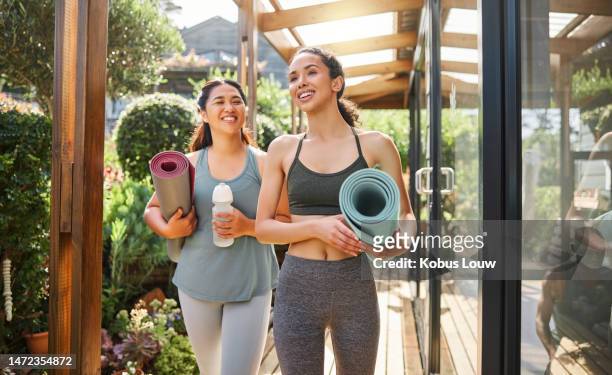 fitness, yoga women walking to class with training gear and water bottle for sports teamwork at wellness center. pilates, workout and healthy people or friends talking of holistic exercise in nature - couple doing yoga stock pictures, royalty-free photos & images