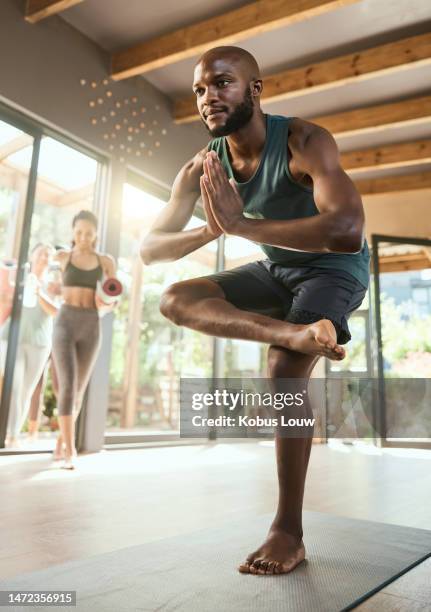 black man, class and yoga training for pose in morning, wellness or happiness with students. personal trainer, women and studio for fitness, exercise or health with balance, mindset and praying hands - man doing yoga in the morning stockfoto's en -beelden