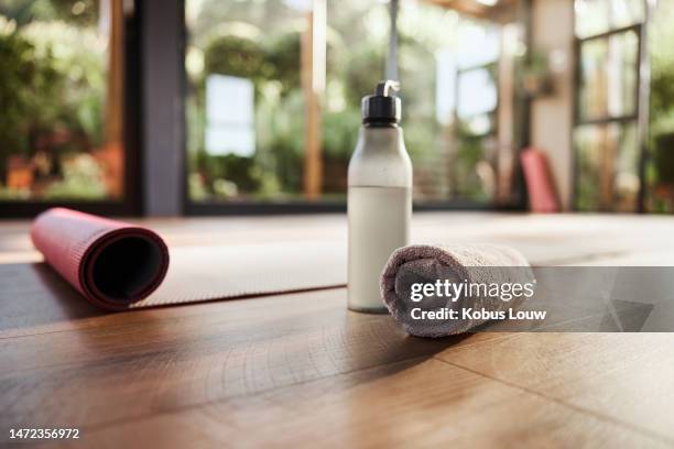 wasser, handtuch und yogamatte im leeren fitnessstudio für wellness, psychische gesundheit oder innere ruhe hautnah. fitness, bewegung und pilates mit stilllebengeräten auf dem boden eines fitnessstudios für ein training - sport drinking bottle stock-fotos und bilder