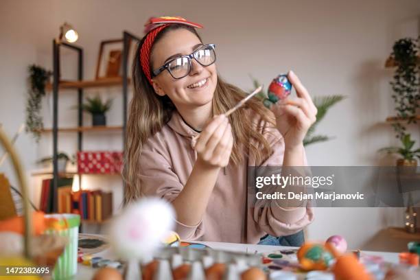 junge frau bereitet osterdekoration zu hause vor - bastelarbeit stock-fotos und bilder