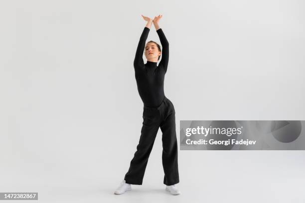 young girl, professional hip-hop dancer in a black clothes performing over a isolated white background with a plenty of copy space. - saut elastique photos et images de collection