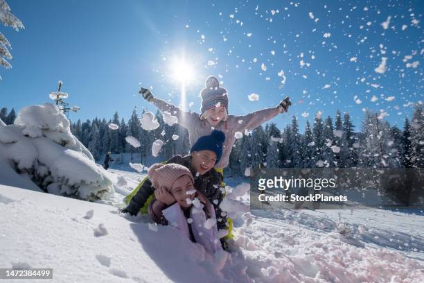 three children are lying on top of each other in the snow. - funny snow skiing stock pictures, royalty-free photos & images