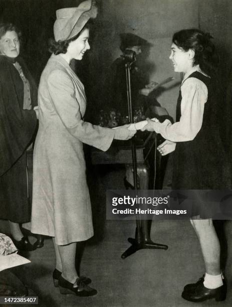 'Prize-Giving', 7 November 1946, . Princess Elizabeth presents prizes at Burlington School in West London. Here a student receives the intermediate...