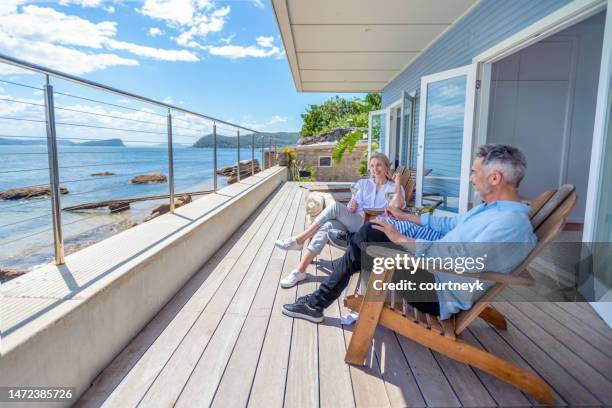 pareja madura bebiendo vino en la terraza de su casa frente al mar - man on the beach relaxing in deckchair fotografías e imágenes de stock