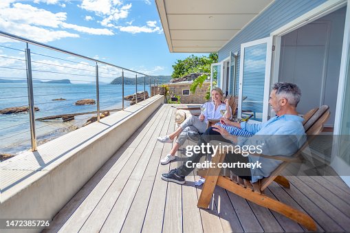 Mature couple drinking wine out on the deck in their waterfront home Mature couple drinking wine out on the deck in their waterfront home