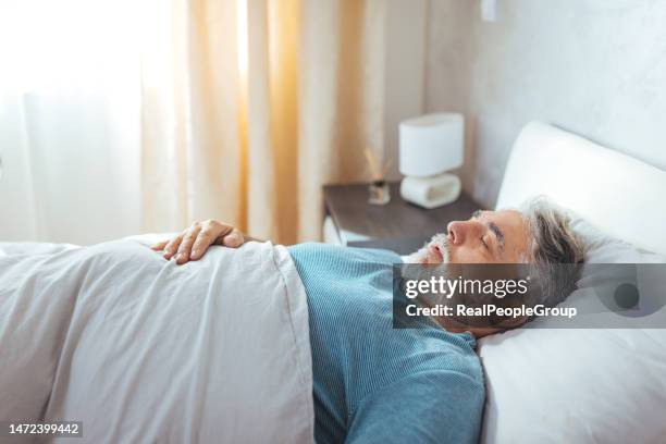 rest and recharge. mature caucasian man sleeping soundly - man sleeping on bed stockfoto's en -beelden