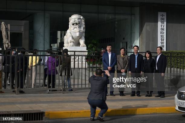 People pose for a photo in front of the office building of China Banking and Insurance Regulatory Commission on March 9, 2023 in Beijing, China.
