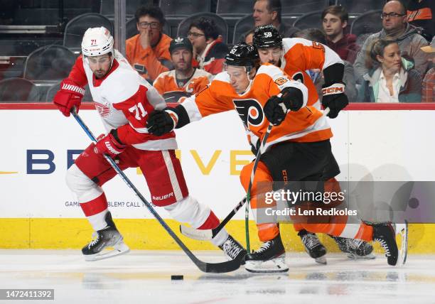 Justin Braun and Tanner Laczynski of the Philadelphia Flyers battle for the puck against Dylan Larkin of the Detroit Red Wings at the Wells Fargo...