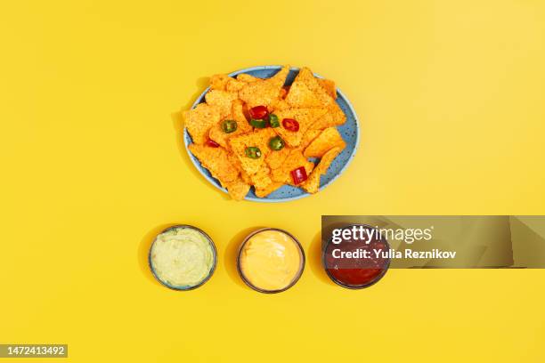 tortilla chips with guacamole, cheese and chili sauces on the yellow background- food knolling - cheese sauce stock pictures, royalty-free photos & images