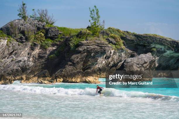 a surfer riding the waves at horseshoe bay beach, bermuda - bermuda people stock pictures, royalty-free photos & images