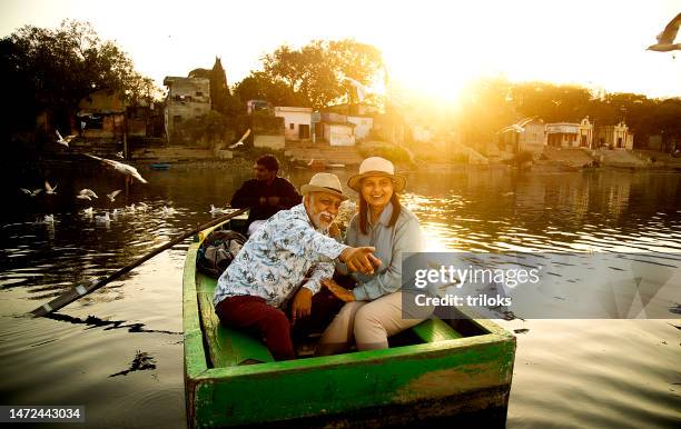 old couple traveling on boat at lake with flock of birds in air - indian elderly couple stock pictures, royalty-free photos & images