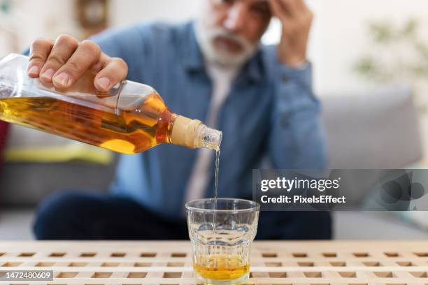 man pours whiskey at home - binge drinking 個照片及圖片檔