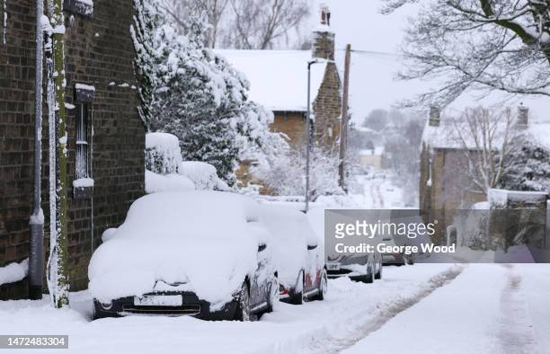 Stranded snow covered cars are parked at the side of a road on March 10, 2023 in Bradford, England. Parts of the UK are under weather warnings for...