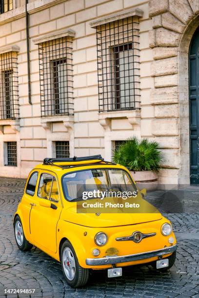 a vintage yellow fiat 500 from 1972 parked in piazza navona in the historic and baroque heart of rome - fiat 500 stockfoto's en -beelden