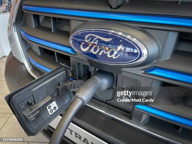 The logo of the Ford Motor Company is displayed on the front grille of an electric Ford Transit being charged in a dealership on March 5, 2023 in...