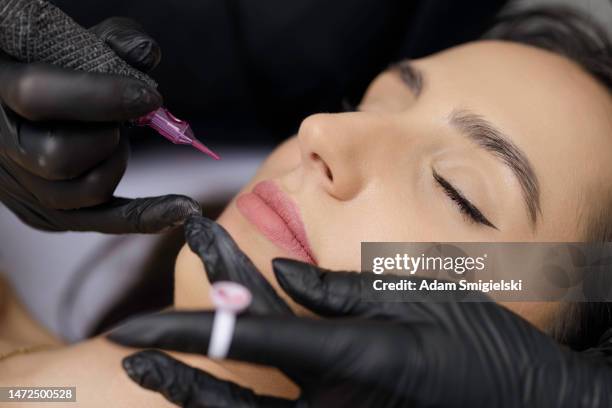 application permanente de maquillage des lèvres par une maquilleuse dans un salon de beauté - maquillage permanent photos et images de collection