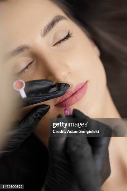 permanentes lippen-make-up auftragen durch eine visagistin in einem schönheitssalon - permanent make up stock-fotos und bilder
